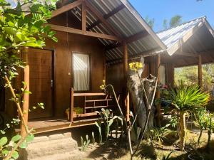 Ce chalet en bois dispose d'une véranda et d'une porte. dans l'établissement Easy Bungalow, à Gili Trawangan