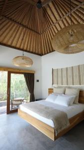 a bedroom with a bed and a large window at petra bianca uluwatu in Uluwatu