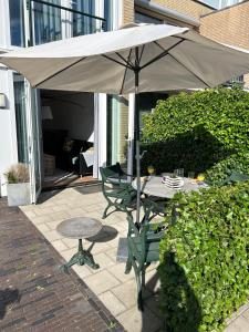 - une table et une chaise sous un parasol sur la terrasse dans l'établissement Noordwijk BB228, à Noordwijk