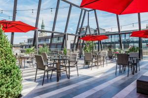 een patio met tafels en stoelen en rode parasols bij Ramada by Wyndham Budapest City Center in Boedapest