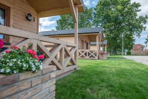 ein Haus mit einem Zaun und Blumen im Hof in der Unterkunft Osada Trzy Siostry in Pobierowo