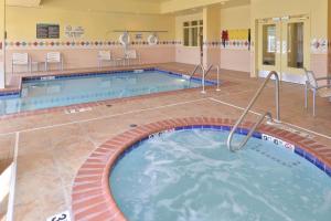 una piscina in ospedale con sedie e tavolo di Hilton Garden Inn Indianapolis/Carmel a Carmel