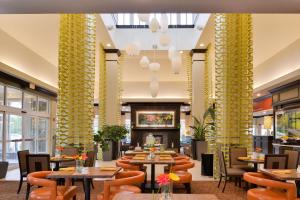 un ristorante con tavoli, sedie e colonne gialle di Hilton Garden Inn Indianapolis/Carmel a Carmel