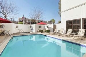 einen Pool mit Stühlen und Tischen sowie ein Gebäude in der Unterkunft Hilton Garden Inn Cupertino in Cupertino