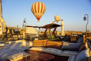 ein Heißluftballon fliegt über eine Dachterrasse mit einer Couch in der Unterkunft Ages in Cappadocia in Uchisar