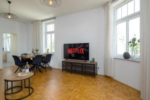 een woonkamer met een televisie en een tafel met stoelen bij LE Vacation 3-Room-Apartment 67qm, Küche, Netflix, Free-TV in Schkeuditz