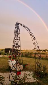 un arco metallico in un campo con un arcobaleno sullo sfondo di 3 ruoniai a Palanga