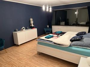 ein Schlafzimmer mit einem großen Bett und einer blauen Wand in der Unterkunft Park Villa Ferienwohnung mit Pool und 3 Schlafzimmer in Uelzen