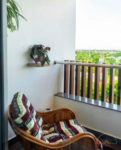 einem Rattanstuhl mit einer Decke auf dem Balkon in der Unterkunft SOLEA 1 bedroom apartment - Central, comfortable, cozy, balcony, pool, gym in Accra