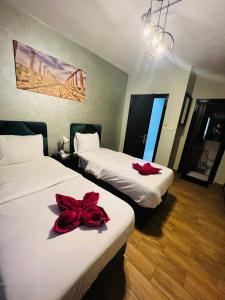 two beds in a room with red bows on them at Sandra Hotel in Amman