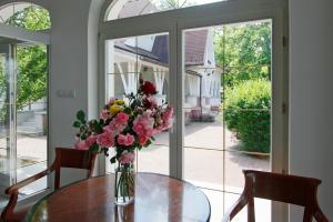 eine Vase mit Blumen auf einem Tisch vor einem Fenster in der Unterkunft Partvilla Balatonboglar in Balatonboglár