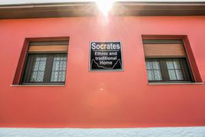 een bord aan de zijkant van een rood gebouw met twee ramen bij SOCRATES Ethnic and traditional Home in Kalabaka