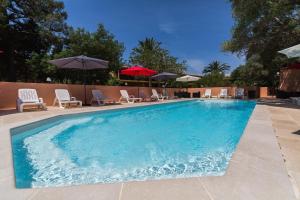 une grande piscine avec des chaises et des parasols dans l'établissement Casa Vecchia rooms + apartments, à Calvi