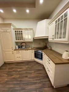 a kitchen with white cabinets and a wooden floor at Robert's Apartment in Celje