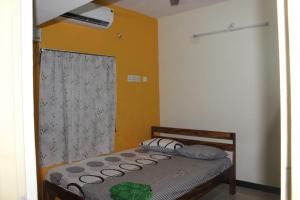 ein Schlafzimmer mit einem Bett in einem Zimmer mit einem Fenster in der Unterkunft Centaurus Homestay near Trichy Airport in Tiruchchirāppalli