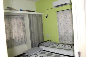 2 Betten in einem Zimmer mit grünen Wänden und Fenstern in der Unterkunft Centaurus Homestay near Trichy Airport in Tiruchchirāppalli