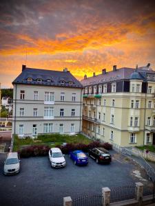 un gruppo di auto parcheggiate in un parcheggio di fronte a un edificio di Apartment Villa Frank a Mariánské Lázně