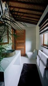 a bathroom with a tub and a toilet in it at petra bianca uluwatu in Uluwatu