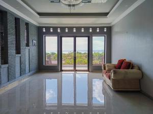 RedDoorz @ Green Homestay Syariah Baubau في Baubau: غرفة معيشة مع أريكة ونافذة كبيرة