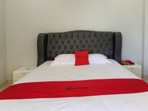 RedDoorz @ Green Homestay Syariah Baubau في Baubau: سرير عليه مخدة حمراء