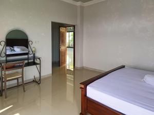 RedDoorz @ Green Homestay Syariah Baubau في Baubau: غرفة نوم بسرير ومكتب وكرسي