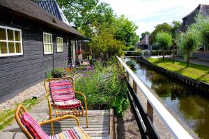 two chairs sitting on a porch next to a river at De Galeriet Giethoorn in Giethoorn