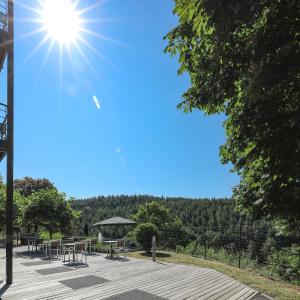 um sol a brilhar sobre um pátio com mesas e cadeiras em Hotel Bô Rivage em Neufchâteau