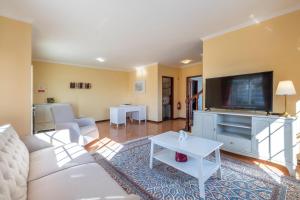 a living room with a white couch and a tv at Casa Vista Mar by GALMI in Calheta