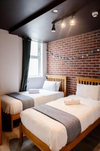 two beds in a room with a brick wall at The Nest Boutique Hostel in Galway