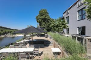 um restaurante com mesas e cadeiras ao lado de um edifício em Hotel Bô Rivage em Neufchâteau