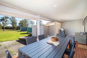 einen blauen Tisch mit Stühlen und eine Terrasse mit Garten in der Unterkunft 'Swan Cottage' Port Stephens Waterfront Solace in Newcastle