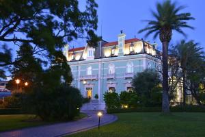 une grande maison blanche avec un palmier en face de celle-ci dans l'établissement Pestana Palace Lisboa Hotel & National Monument - The Leading Hotels of the World, à Lisbonne