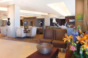 una hall di un hotel con sedie e tavolo con fiori di Holiday Inn Johannesburg-Rosebank, an IHG Hotel a Johannesburg