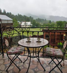 a table on a balcony with two cups and chairs at Emerald House in Mykulychyn