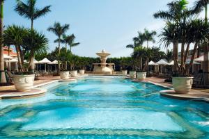 une piscine dans un complexe avec des palmiers et une fontaine dans l'établissement The Venetian Macao, à Macao