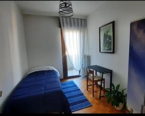 een slaapkamer met een blauw bed en een tafel bij Verdisuite - Trento centro - Parcheggio privato gratuito in Trento