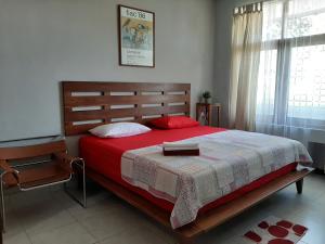 een slaapkamer met een bed met een rode deken en een raam bij rumah566 in Yogyakarta