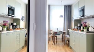 a kitchen with white cabinets and a dining room with a table at Apartments am Dom in Naumburg