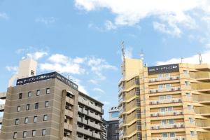 zwei hohe Apartmenthäuser vor einem blauen Himmel in der Unterkunft HOTEL Third Place Hakata in Fukuoka