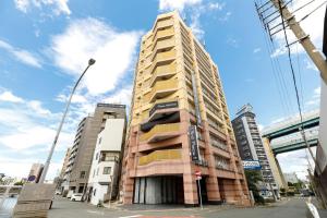 ein hohes Gebäude in einer Stadtstraße mit Gebäuden in der Unterkunft HOTEL Third Place Hakata in Fukuoka