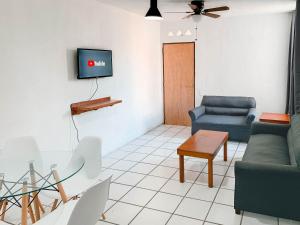 a living room with a couch and a tv on a wall at Departamentos 1E in Puerto Vallarta