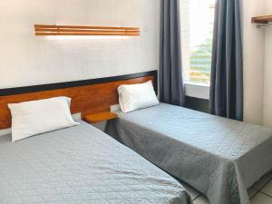 two twin beds in a room with a window at Departamentos 1E in Puerto Vallarta