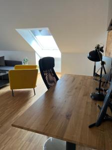 a living room with a wooden table and a yellow chair at New Age Boardinghaus Bad Wimpfen in Bad Wimpfen