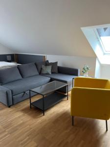 a living room with a blue couch and a yellow chair at New Age Boardinghaus Bad Wimpfen in Bad Wimpfen