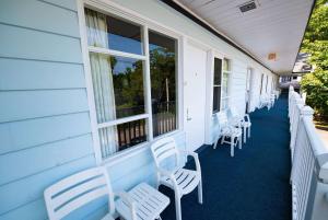 eine Reihe weißer Stühle auf der Veranda eines Hauses in der Unterkunft Days Inn by Wyndham Bar Harbor in Bar Harbor