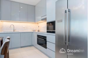 a kitchen with white cabinets and a stainless steel refrigerator at Dream Inn - Address Beach Residence Fujairah - Premium Apartments in Fujairah