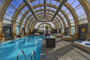 uma piscina interior com um tecto de vidro arqueado e uma piscina em The Ritz-Carlton, Santiago em Santiago