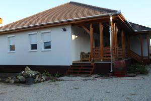 Cette maison blanche dispose d'une terrasse couverte en bois et d'escaliers. dans l'établissement Borács Winedégház, à Bogács