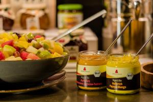 a bowl of fruit next to two jars of honey at Motel One München - Deutsches Museum in Munich