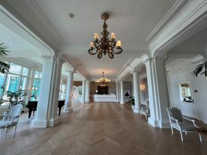 ein großes Zimmer mit einem Kronleuchter und einem Flur mit Stühlen in der Unterkunft Hotel Eden Palace au Lac in Montreux